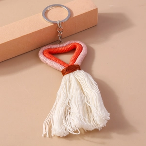 Close-up of handmade woven heart keychain with orange pink cotton tassels and metal ring