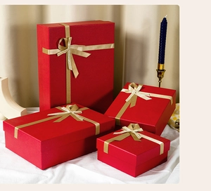 Set of four red gift boxes in various sizes with golden ribbon bows and festive decor