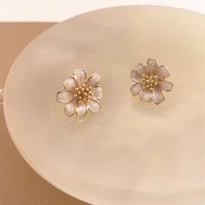 Macro shot of elegant floral stud earrings with pearlescent white petals and gold details