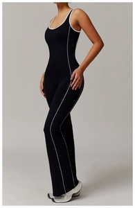 Detail eines schwarzen Yoga-Jumpsuits mit ausgestelltem Bein und weißer Paspelierung