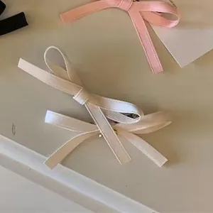 Detailed view of layered ribbon bow hair clips in cream, soft pink and black colors