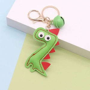 Close-up of green PU leather dinosaur keychain with red fins, gold ring and a small bell