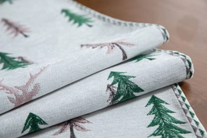 Close-up of woven jacquard table runner featuring green pine trees and pink deer