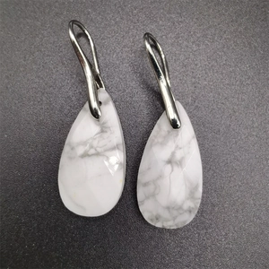 Macro detail of white marble teardrop earrings with elegant silver metal hooks