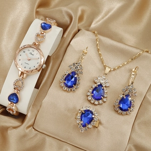 Luxurious rose gold watch and jewelry set with teardrop blue gems on beige silk