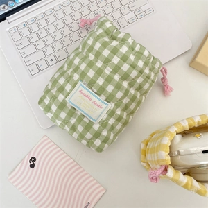 Detalle de la funda acolchada para cámara con cuadros verdes y blancos y cordón rosa