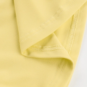 Macro shot of double-needle stitching and high-quality hem detail on yellow knit set