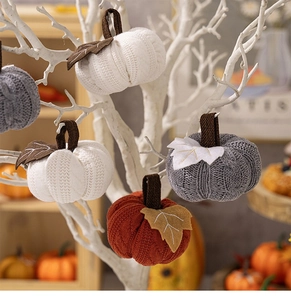 Detail showing knitted pumpkin decorations in white and orange on decorative branches