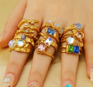 Detailed view of irregular gold rings with various colored gemstones on a hand