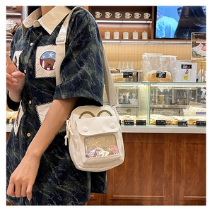 Detail of cream canvas messenger bag with a clear window and cute bear ear design