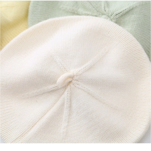 Detailed knit texture of baby wool beret hats in white, light yellow, and green colors
