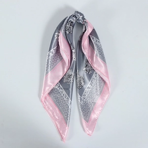 Detail of grey satin square scarf with pink borders and white floral patterns tied in a knot