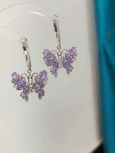 Detailed close-up of zircon butterfly earrings with purple stones on silver metal