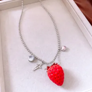 Detail of strawberry pendant necklace with star and zircon charms on bead chain