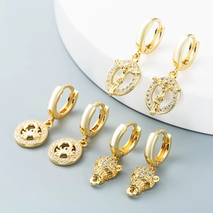 Detailed view of gold hoop earrings with leopard head, crown and cross pendants