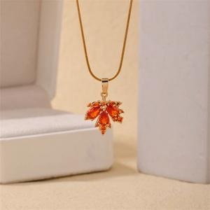 Golden maple leaf pendant necklace with orange gemstone on a sleek snake chain