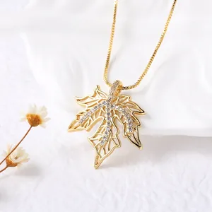 Golden maple leaf pendant necklace with crystals on white background