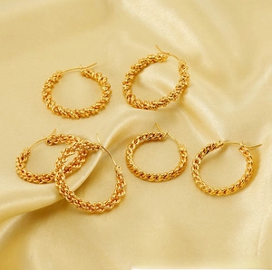 Detailed view of multiple gold twisted rope hoop earrings on silk fabric background
