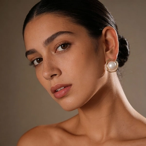 Close-up of minimalist pearl earring with gold ring base worn by elegant model