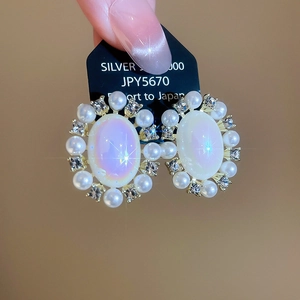 Close-up of vintage oval iridescent opal earrings with pearls and crystals set in gold