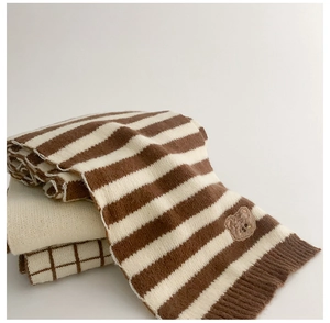 Close-up of a cozy striped knit scarf featuring a cute embroidered bear patch detail