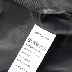 Close-up of garment care label on dark gray wool coat showing 100% polyester material