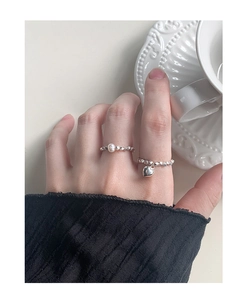Detail of silver S925 rings worn on hand, featuring a pearl and heart charm accent