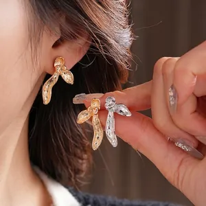 Irregular metal orchid petal stud earrings in gold and silver finish on model