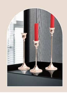 Detail van drie roségouden metalen kandelaars met slanke stelen en ronde bases