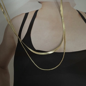Detailed view of layered gold snake chain and box chain necklace on model neck