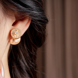 Close-up of elegant gold plated zircon and pearl earrings worn by a female model