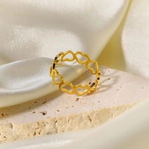 Vue détaillée de la bague cœur évidé plaquée or 18 carats sur fond de soie beige et pierre