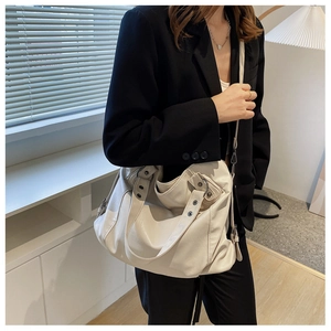 Close-up of cream canvas tote bag with adjustable straps on a black blazer