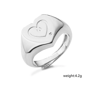 Macro shot of silver heart signet ring with engraved lines and tiny zircon detail