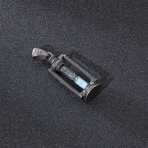 Macro shot of retro hourglass pendant with blue sand and dark metallic finish