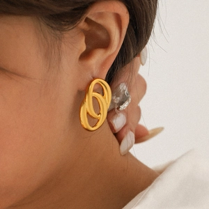 Close-up of elegant gold interlocking hoop earrings worn by a model for a luxury look