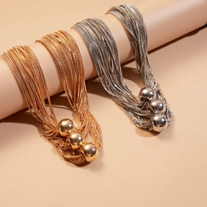Detail of layered gold and silver snake chain necklaces with smooth metal beads