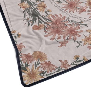 Close-up of pink flannel blanket with floral patterns and durable blue hemmed edges