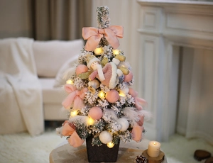 Close-up of a 40cm flocked Christmas tree with pink bows, white feathers and warm LED lights