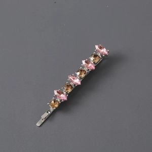 Detail shot of a metal hair clip featuring alternating pink and gold marquise crystals