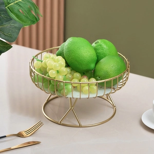 Nordic gold metal fruit basket with marble base holding fresh green lemons and grapes