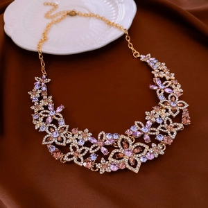 Detailed view of floral necklace with pink and purple rhinestones on a brown fabric