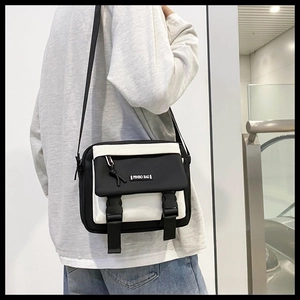 Detail view of black and white crossbody bag with buckle closure and adjustable strap