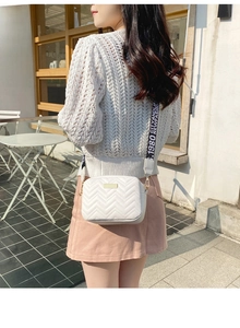 Close-up of white quilted crossbody bag with a stylish black and white printed wide strap