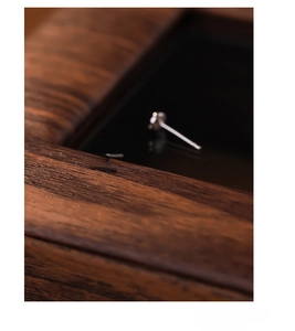 Macro shot of minimalist S925 sterling silver cross stud earrings on dark wood