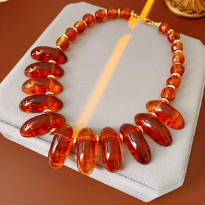 Detail of vintage geometric amber beaded necklace with golden spacers on textured pad