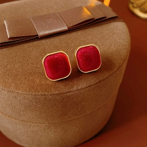 Detail of red velvet square stud earrings with gold trim on a vintage jewelry box