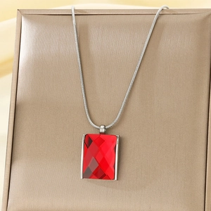 Detailed close-up of a square red glass pendant on a silver snake chain over a gift box