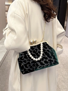 Dark green velvet shell bag with leopard print and pearl handle carried by a model