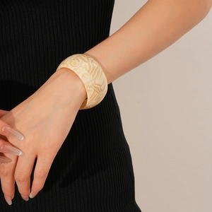 Close-up of a wide marble-patterned acetate open cuff bracelet on a model's wrist